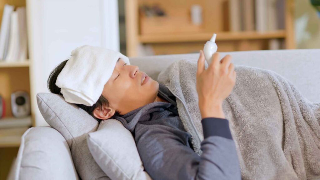 man with a fever looking at his thermometer